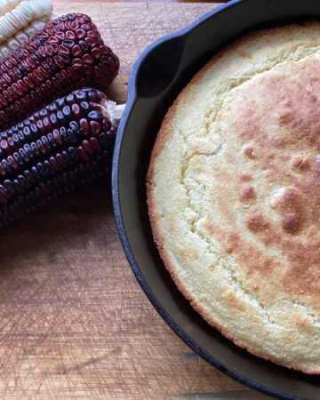 crispy and golden cornbread in a cast iron skillet with melted butter
