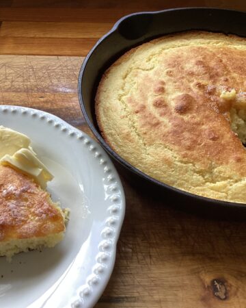 corn bread sliced and on a white plate with a pat of butter